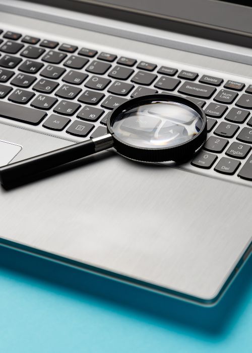 A magnifying glass on a laptop which is in the midst of a security scan.